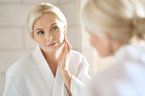 A woman looks in the mirror at her skin. Your skincare routine doesn't have to end when you go to bed. In fact, how you sleep can play a significant role in how your skin ages over time. Read more about how our anti-aging pillow can help.