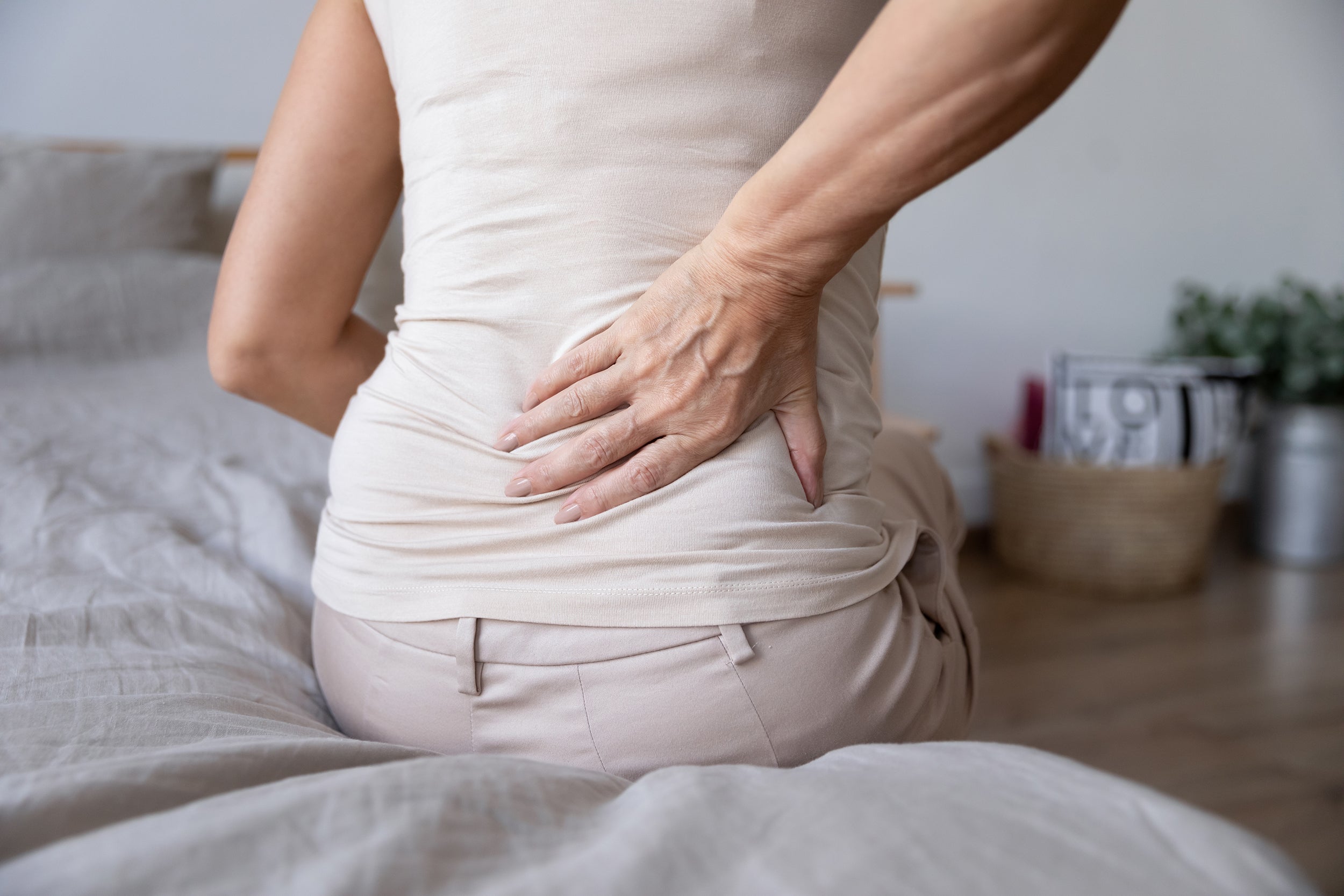 A woman clutches her back in pain. Discover the best sleeping positions for sciatica relief. Learn elevation angles, pillow placement, and positioning strategies that reduce nerve pain tonight.