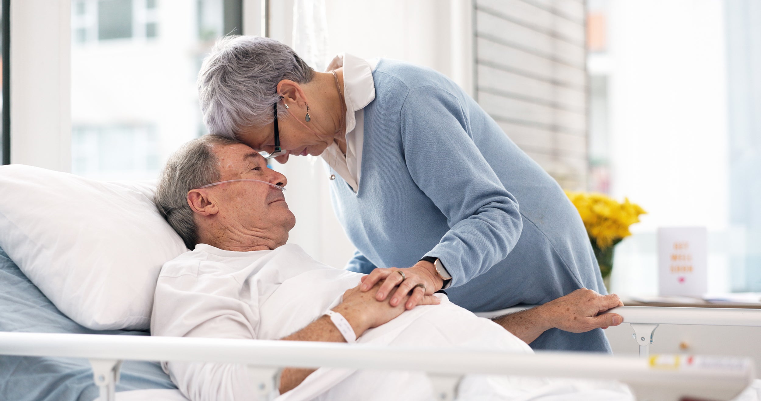 A woman comforts a man in a hospital bed. Cancer pain is complex — but manageable. Learn how medication, therapy, and sleep positioning support comfort and quality of life during treatment.