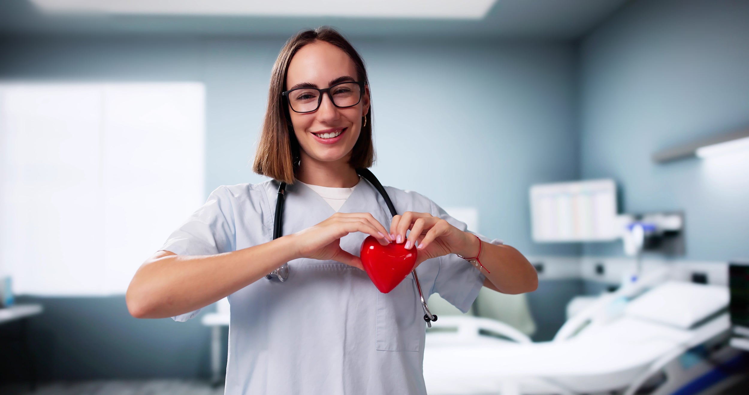 Doctor holding a plastic heart. Recovering from surgery requires plenty of rest. Get better sleep and better healing from our heart surgery pillow.