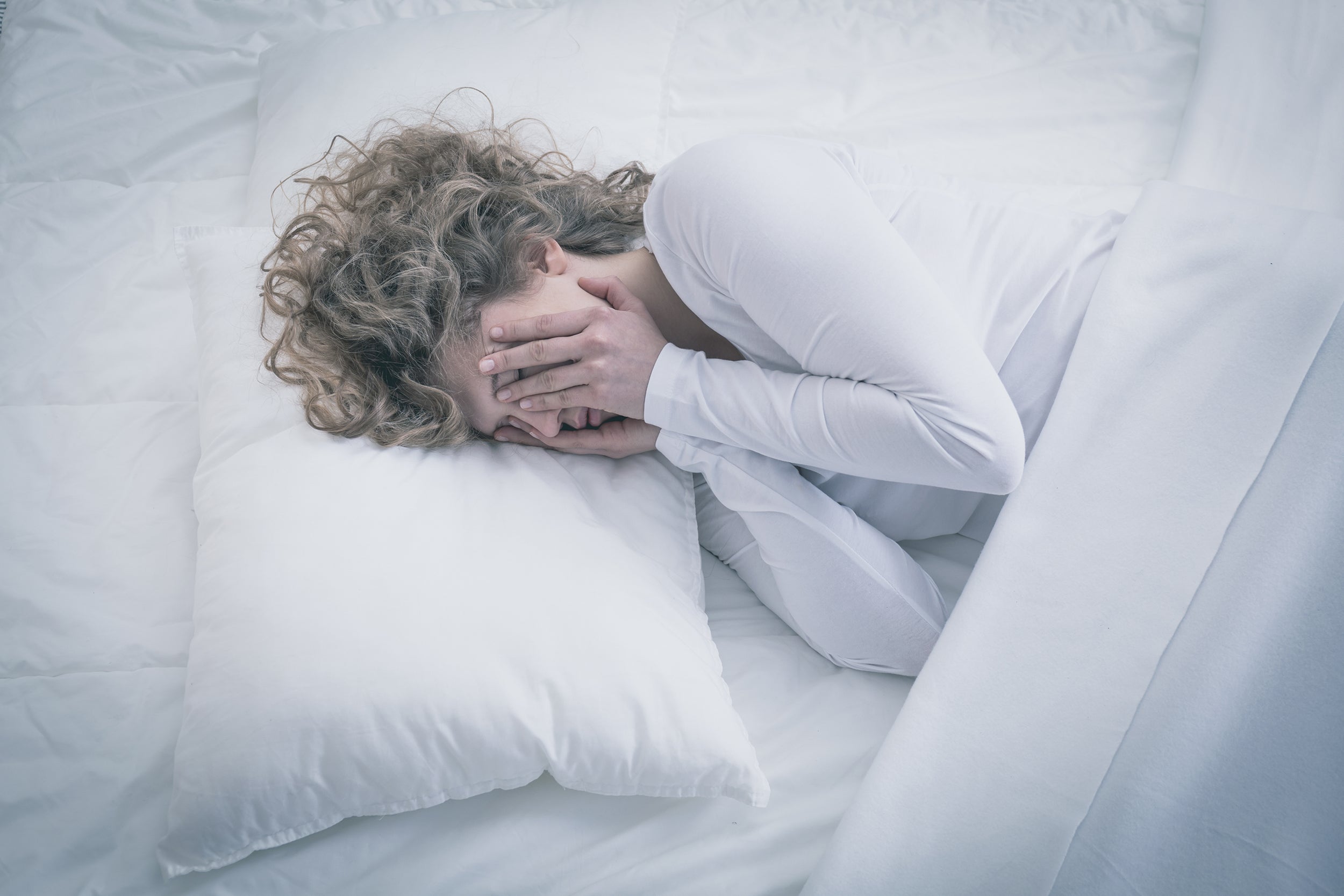 A woman struggles to sleep. Learn how to sleep after BBL surgery using elevated positioning that protects transferred fat cells. Complete guide to BBL recovery sleep positions and equipment.