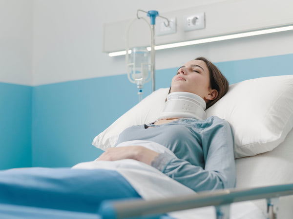 A woman rests in a hospital bed following neck surgery. Learn more about how to get the rest and sleep you need after cervical neck surgery in our comprehensive guide.