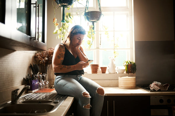 A woman looks at her phone. Sleep after Lipo 360 is tough. This guide covers what to do and what to avoid.