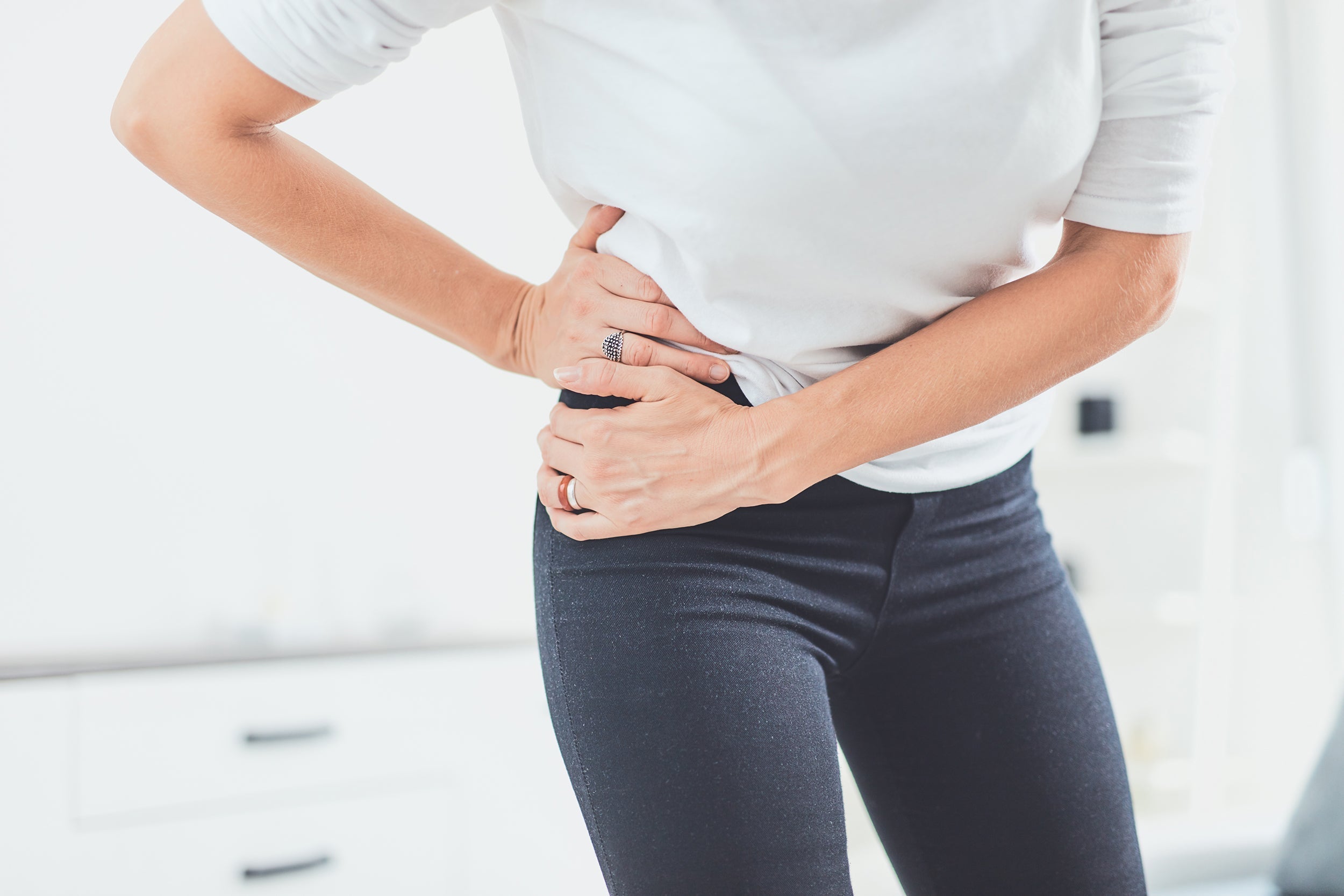 A woman clutches her hip in pain. Hip pain affects millions worldwide and its impact on sleep can be devastating. Learn how to sleep with hip pain in our complete guide.