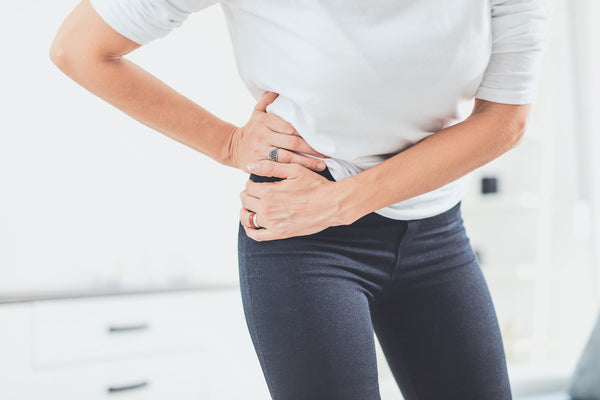 A woman clutches her hip in pain. Hip pain affects millions worldwide and its impact on sleep can be devastating. Learn how to sleep with hip pain in our complete guide.