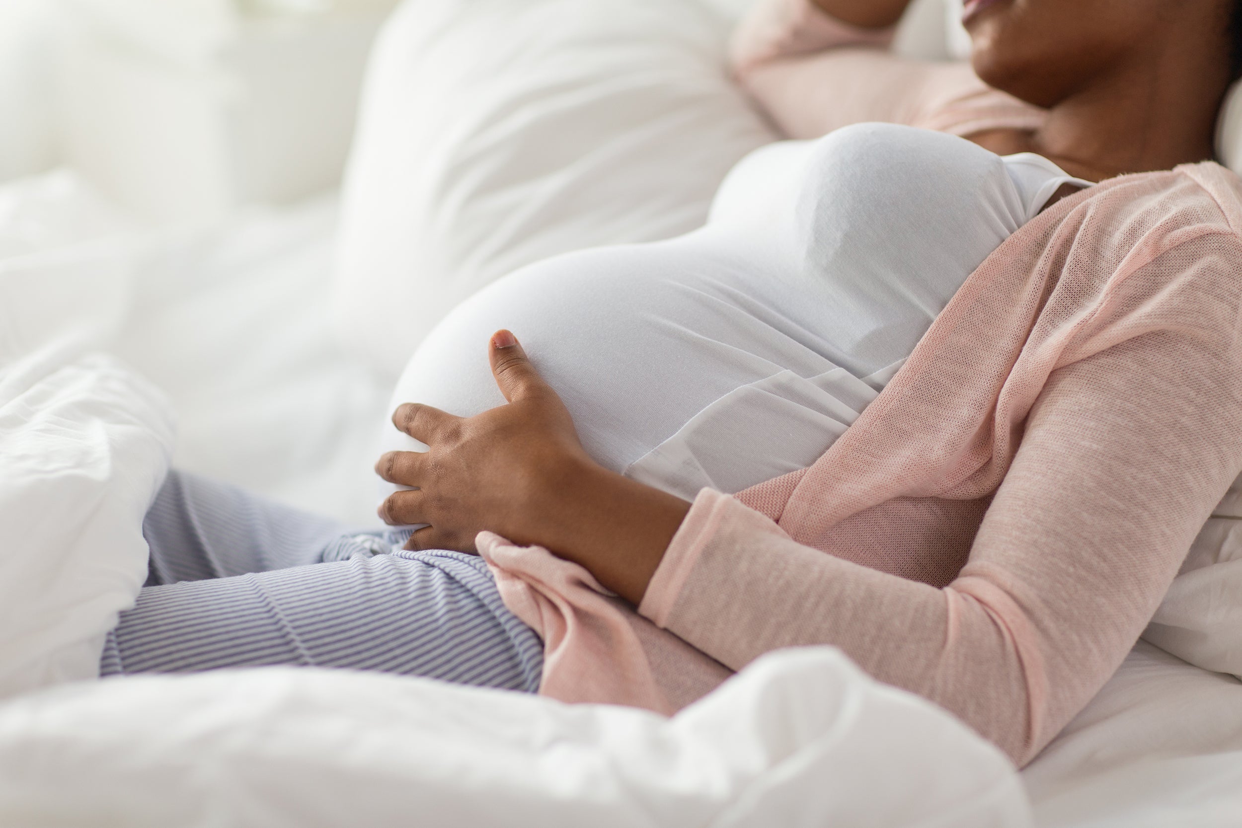A pregnant woman rests in bed. Learn how to use a pregnancy pillow in our comprehensive guide and get the nurturing sleep you and your growing baby deserve.