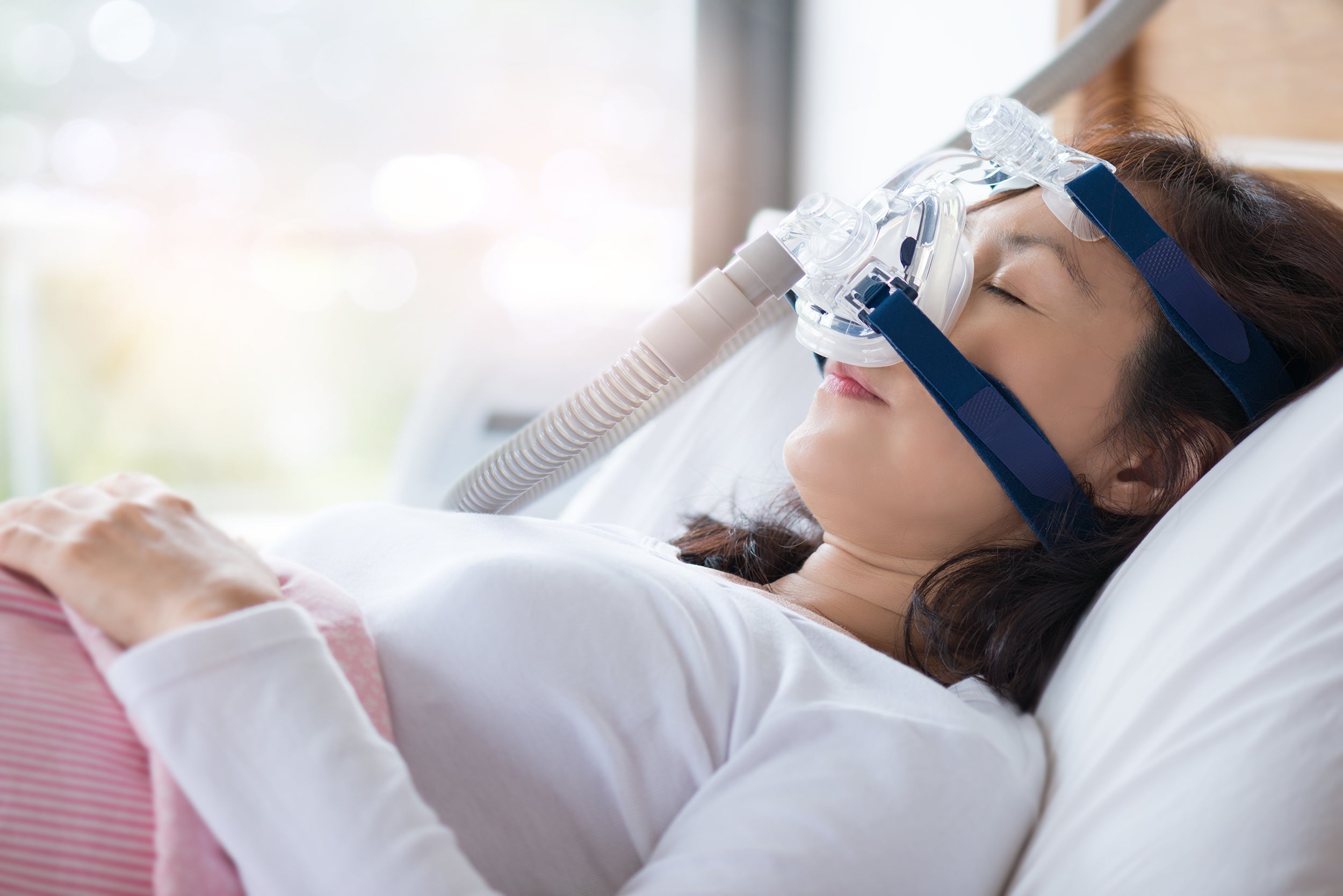 A woman sleeps with a sleep apnea mask covering her nose. If you're dealing with sleep apnea, you've probably tried everything to get better sleep. A sleep apnea pillow can help. 