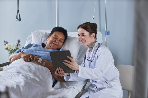 A doctor talks to a woman in a hospital bed. If you're preparing for gastric sleeve surgery, be sure to check out our essential healing guide on how to sleep after gastric sleeve surgery and get the rest you deserve.