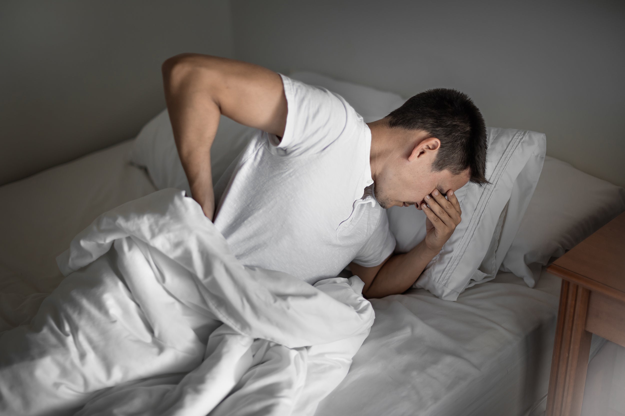 A man struggles to sleep. If you've recently been diagnosed with pudendal neuralgia, sleep can be challenging. Get rest and relief with our complete guide on how to sleep with pudendal neuralgia,.