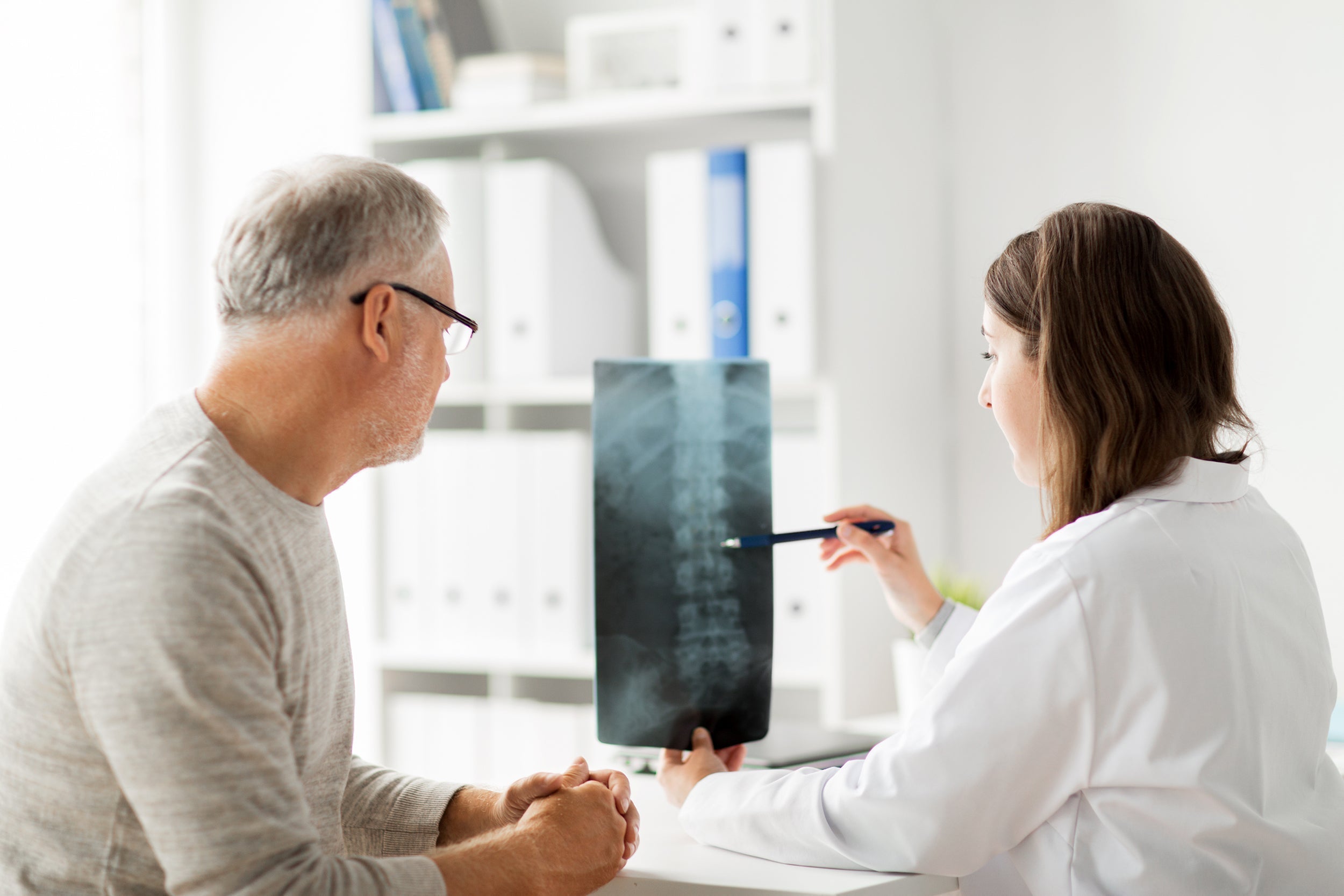A doctor reviews an X-ray of a patient's spine. In preparing for epidural steroid injection, how you sleep can have a big impact on healing and the overall results. Read more in our complete guide.