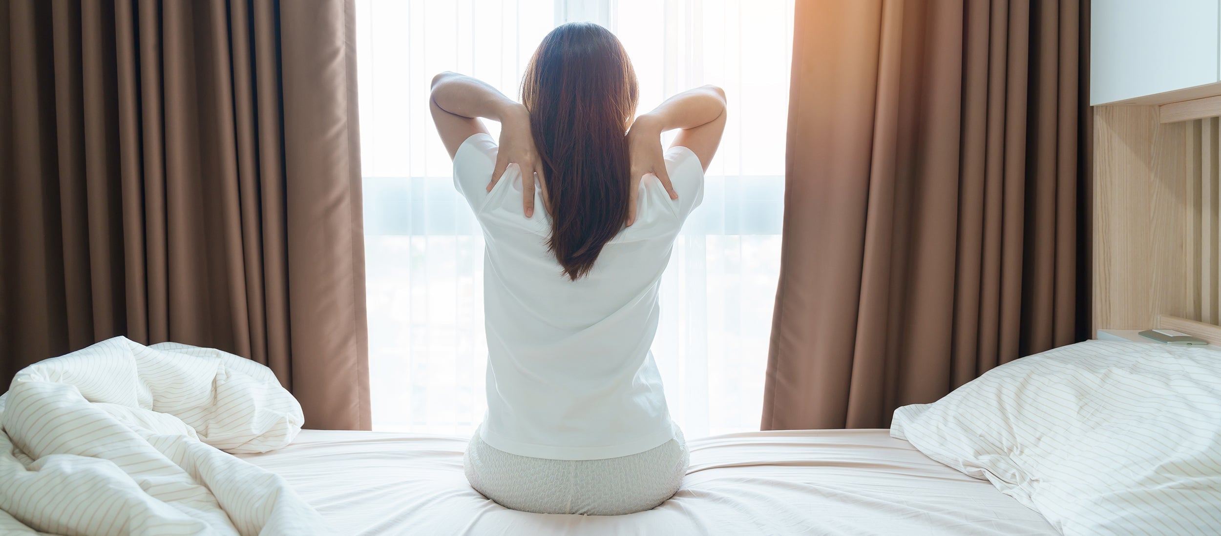 A woman clutches her upper back. End morning upper back pain with proper sleep positioning. Learn why elevated back sleeping supports your thoracic spine and prevents shoulder blade strain all night.