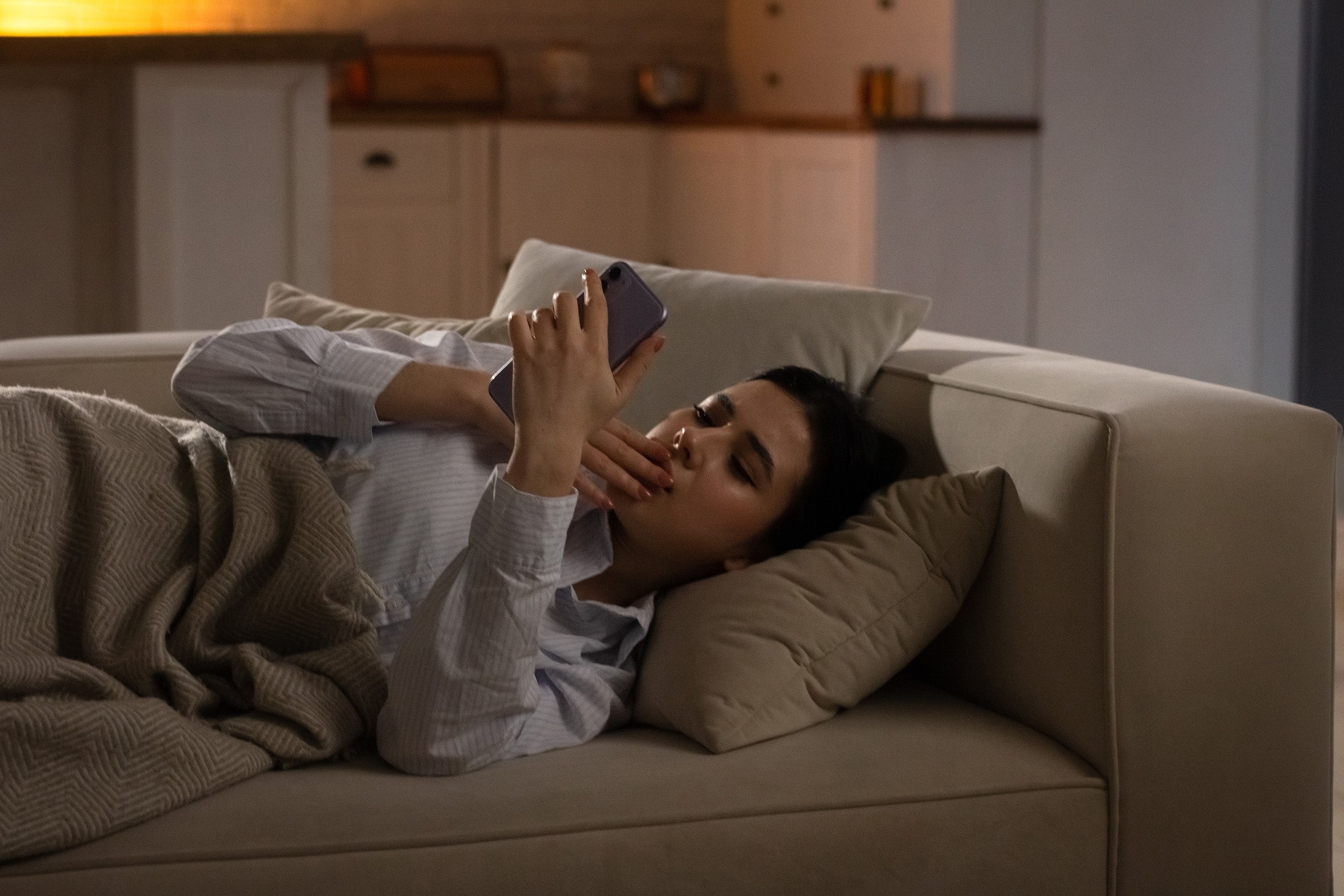 A woman rests on the couch. Wondering when you can finally side sleep after breast augmentation? Get the week-by-week timeline, what affects your clearance, and how to make the transition comfortable.