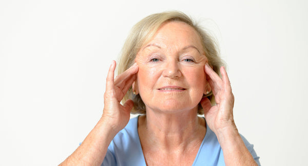 A woman looking at her own face. Planning a facelift? Explore the best facelift recovery must-haves and be prepared well before surgery day.