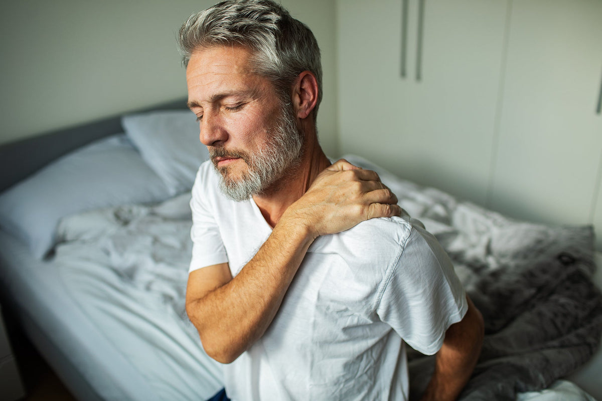 A man with shoulder pain. Frozen shoulder pain waking you up at night? Learn the best sleep positions, proper pillow support, and how to prep before surgery for real, lasting relief.