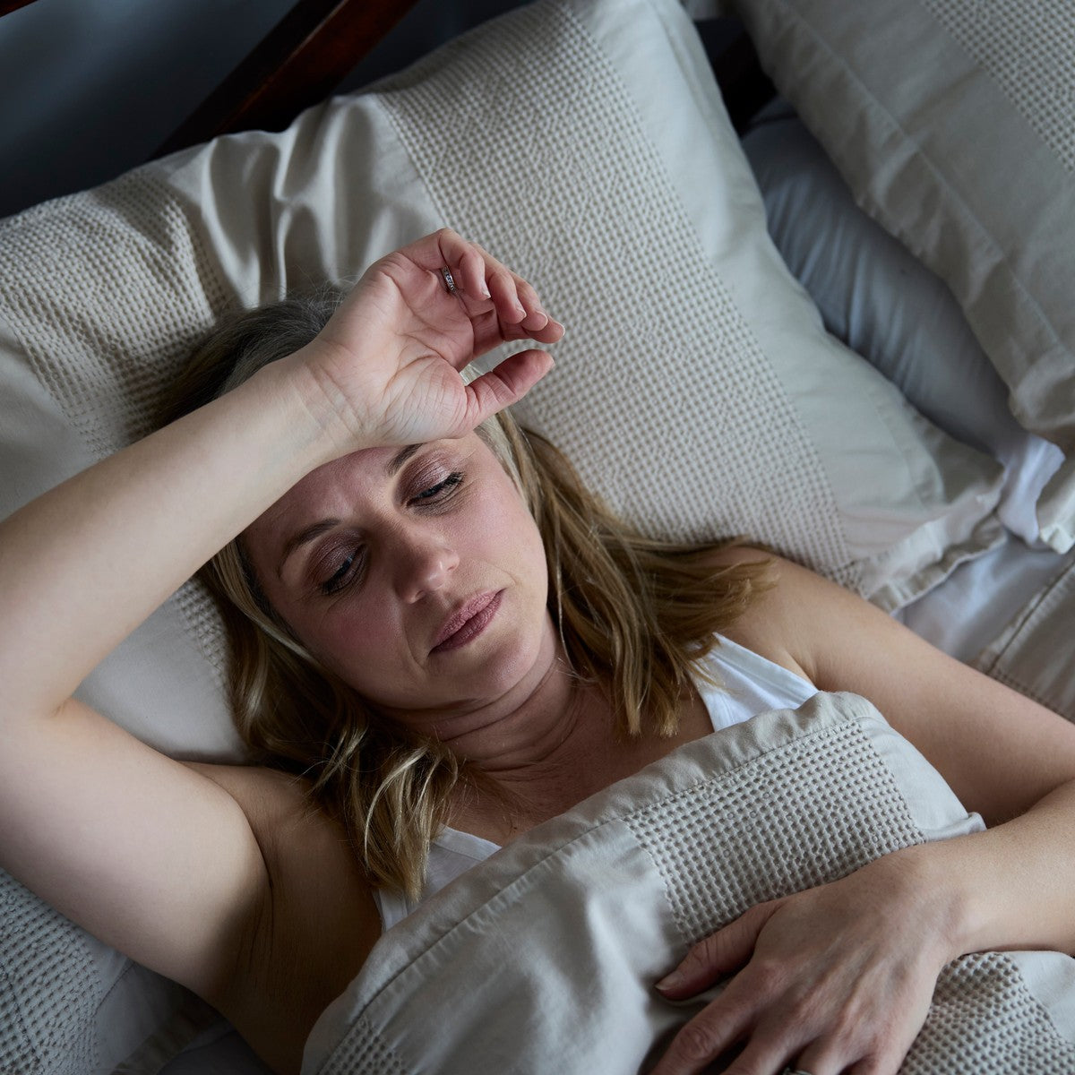 Woman lying awake in bed, struggling to get comfortable during post-surgical recovery