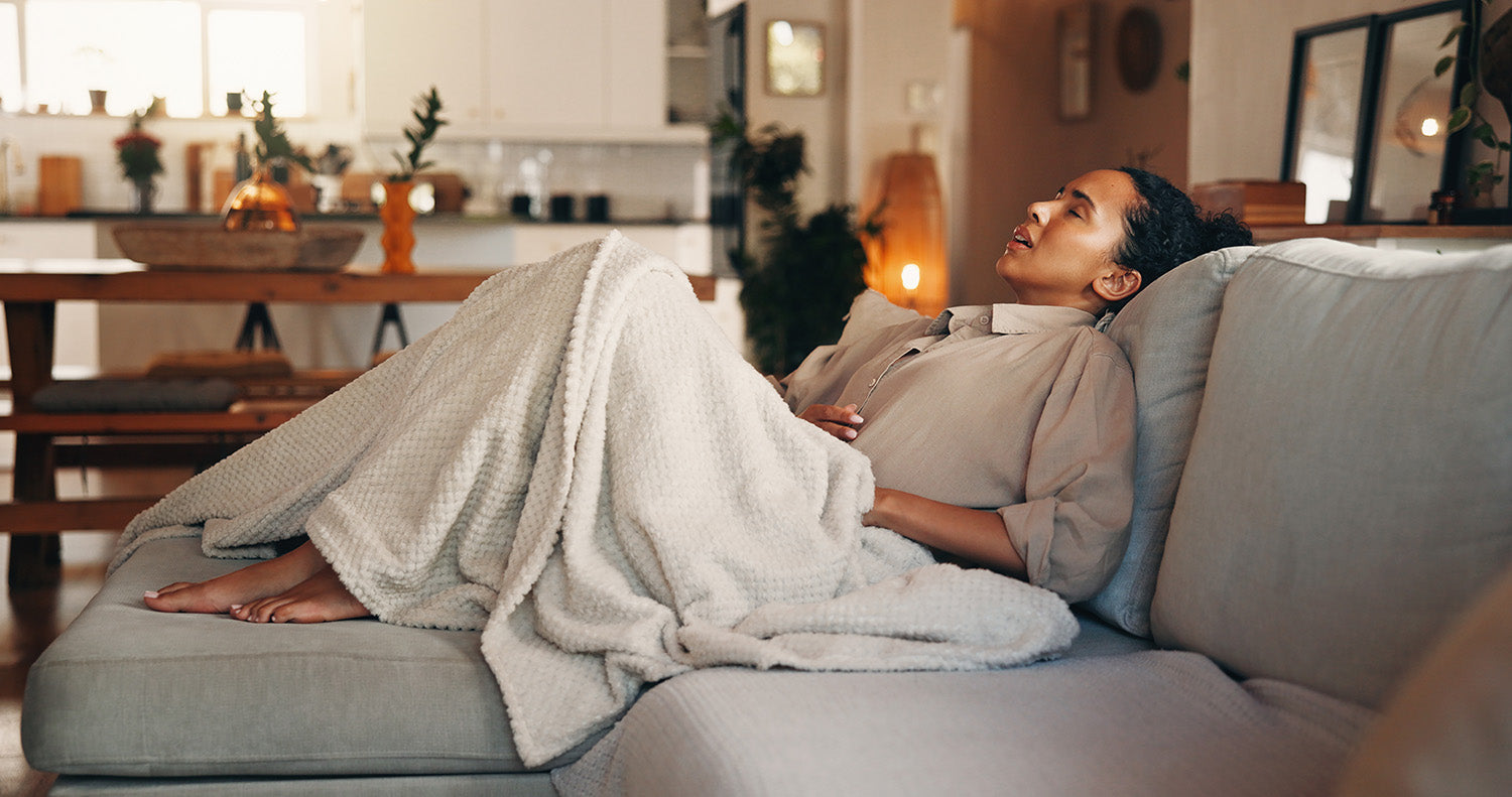 A woman in discomfort. How to sleep with acid reflux on GLP-1 medications: the causes, the ideal 30-45 degree sleep angle, and the positioning system that holds that angle all night.