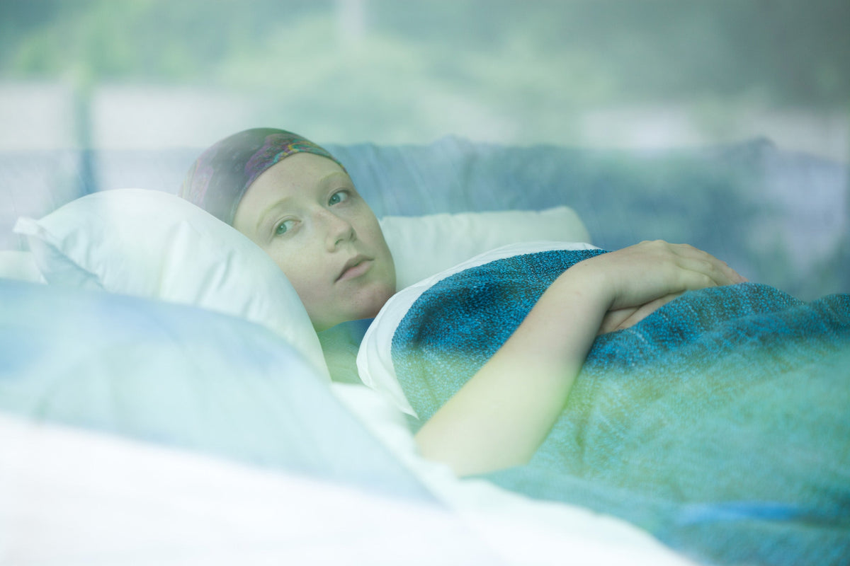 A woman with cancer rests in bed. Struggling to sleep during cancer treatment? Learn when to seek professional support and which bedtime habits can truly improve your sleep quality.