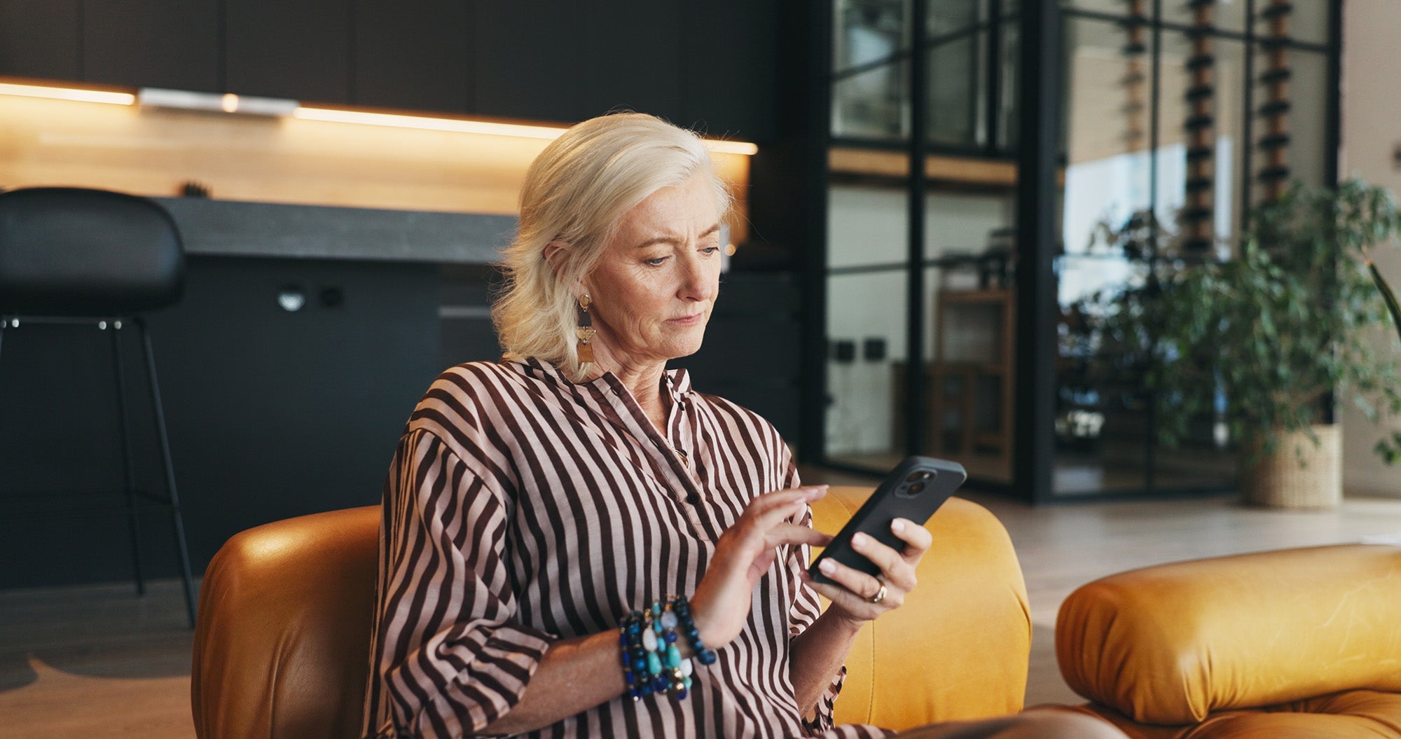 A woman looks at her phone. Explore our complete guide on mastectomy recovery must-haves, created by a breast cancer survivor, and be prepared before surgery.