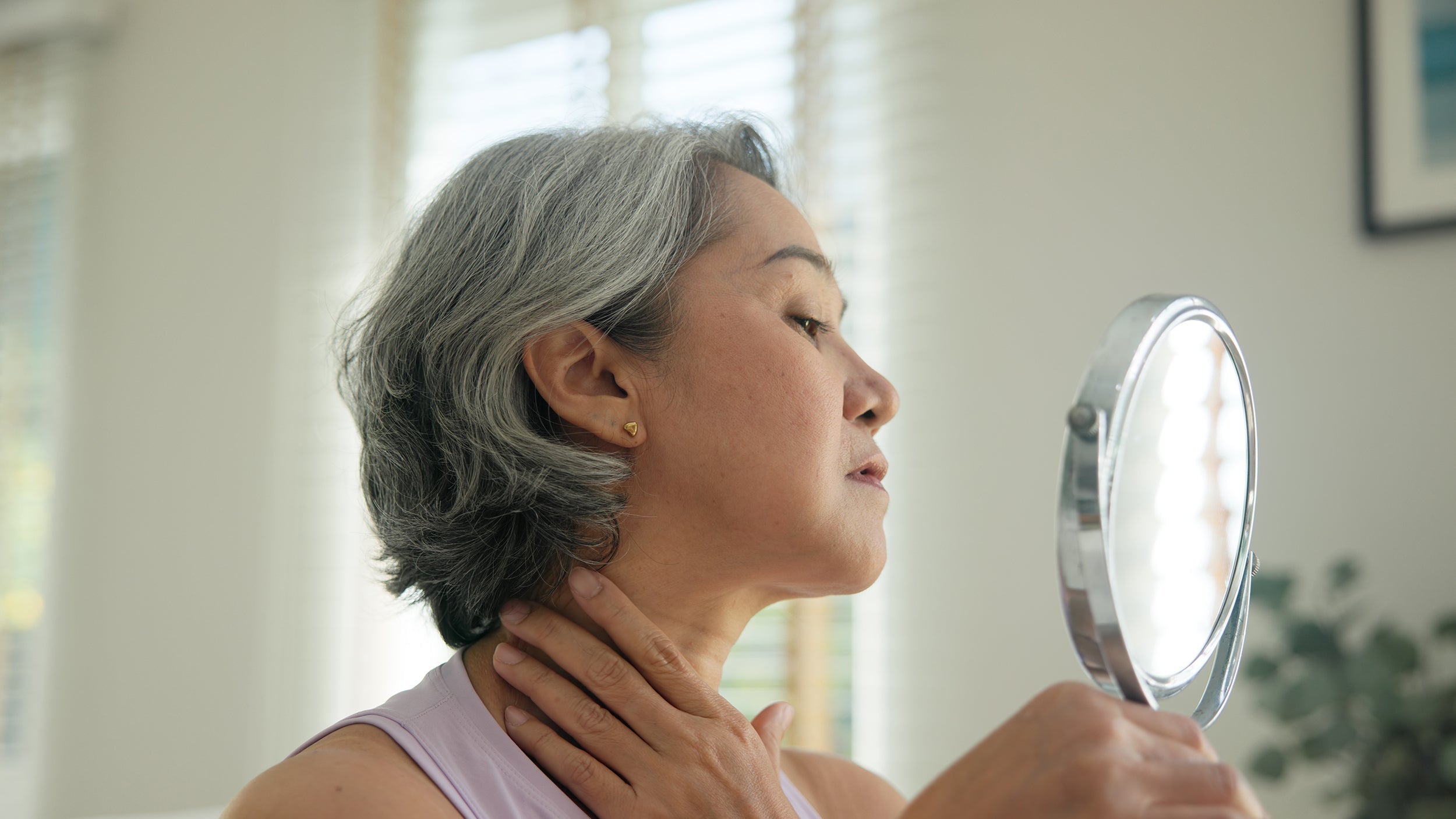 A woman looking in the mirror. Surgeons require elevated sleep for weeks after cosmetic surgery. See the 14 recovery must-haves that proactive patients should prepare before their procedure date, not after.