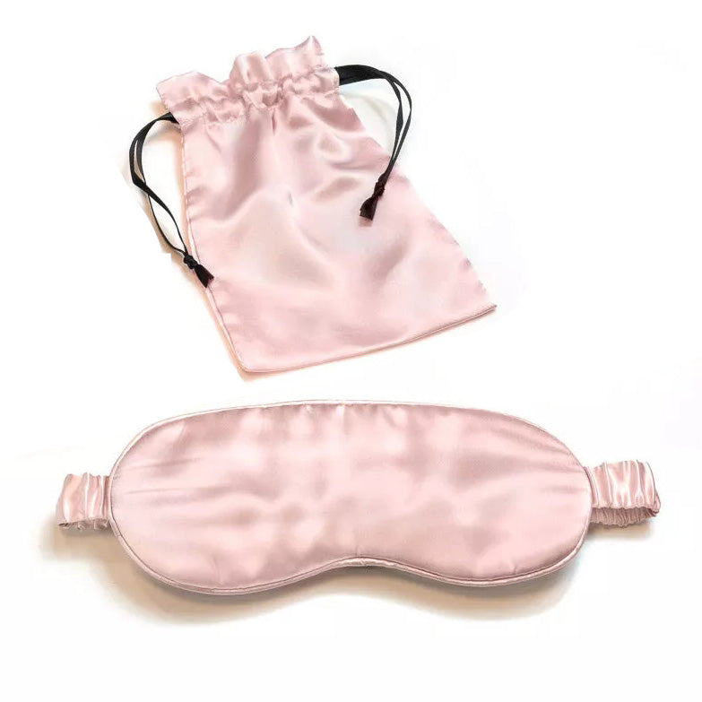 A light pink Mulberry Silk Sleep Eye Mask with silk covered elastic strap is shown below a matching satin drawstring pouch on a white background.