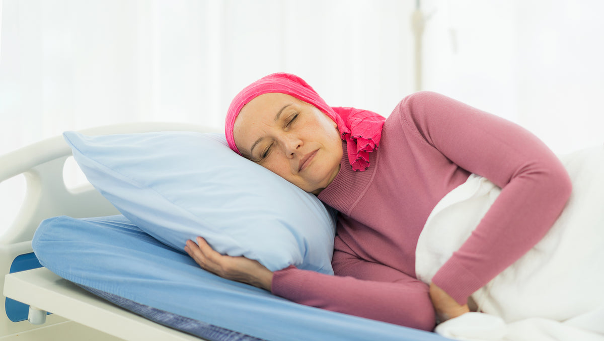 A woman rests in bed. Sleep guides for every stage of breast cancer: diagnosis, mastectomy and lumpectomy recovery, chemo, radiation, and caregiving. Plan your setup before surgery.