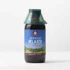 A bottle of Serious Relaxer & Muscle Tension herbal supplement with a green cap sits against a light background; its label displays a peaceful mountain and starry night scene, emphasizing sleep aid and muscle tension relief benefits.
