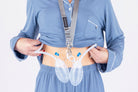 A person in blue pajamas lifts their shirt to reveal two surgical drains secured by the Sleep Again Surgical Drain Holder, ensuring effective and comfortable post-operative drain management.