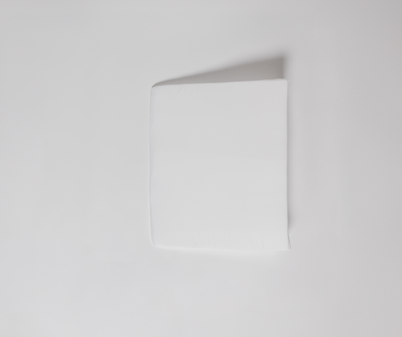 An Individual Wedge Pillow Sold Separately rests on a plain white surface, casting a soft shadow to the upper right—mirroring the crisp, clean feel of customizable bedding in a serene bedroom.