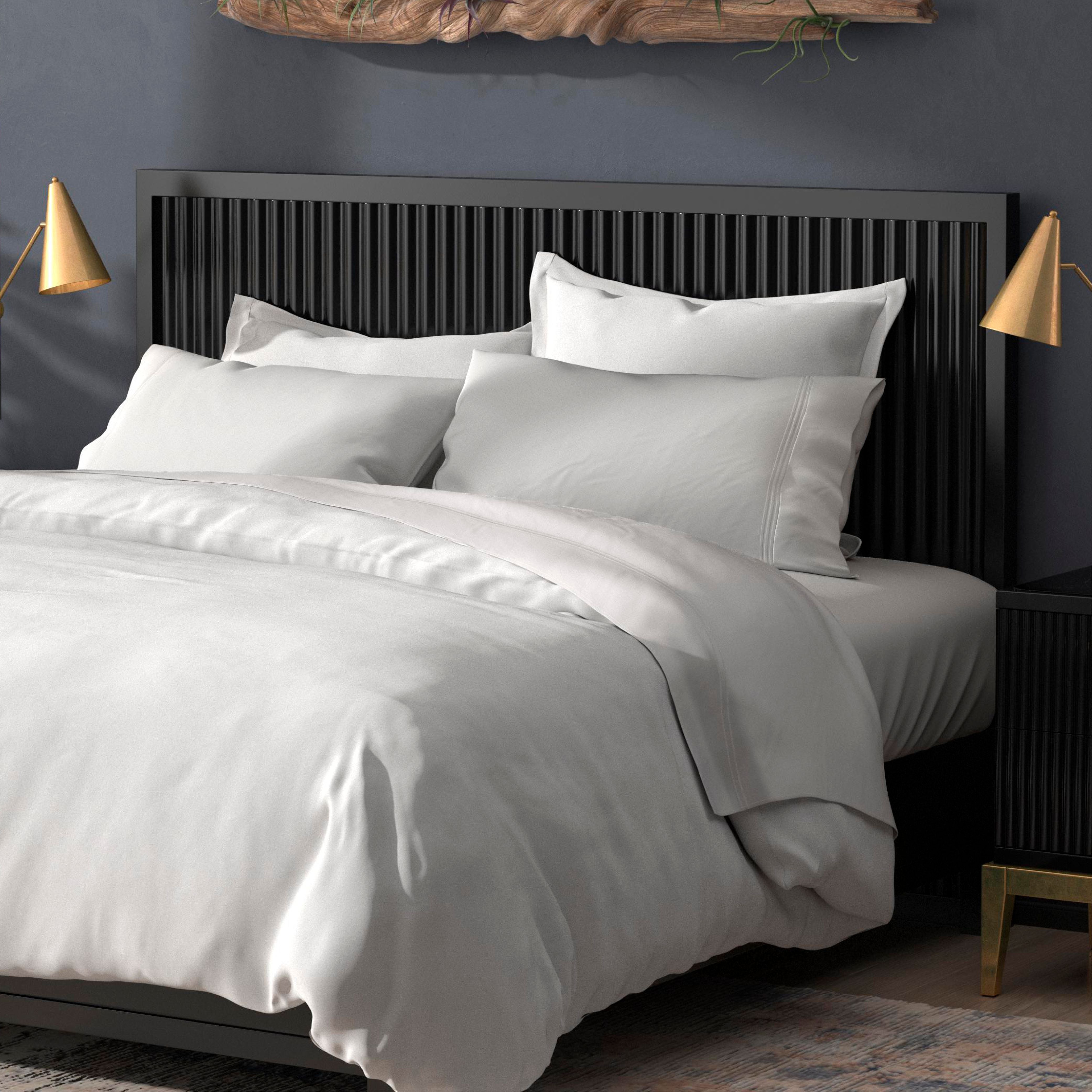 A neatly made bed with a PureCare Duvet Cover | Cooling Bamboo, white bedding and pillows, a black slatted headboard, gold wall-mounted lamps, and a dark wall background.